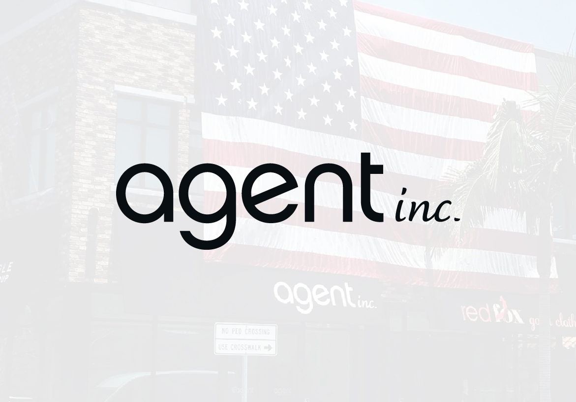 AGENT INC. real estate logo in white, featuring clean typography, positioned over a brightly lit American flag background.