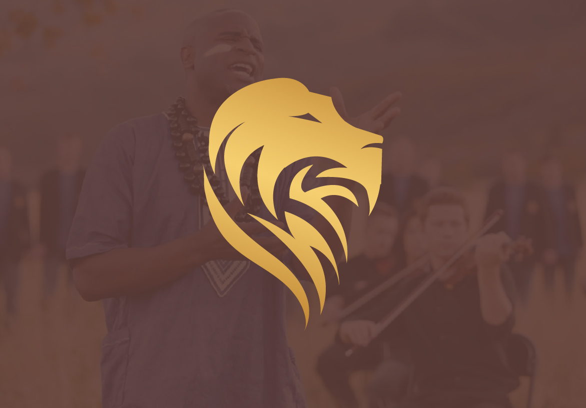 Gold lion head logo symbol for singer Alex Boyé, overlaid on a moody, soft-focus background of a musical performance.