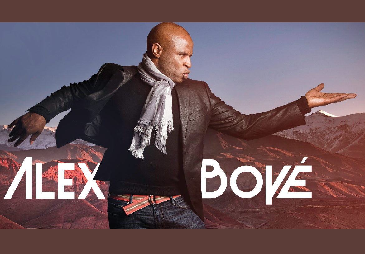 Dynamic action shot of singer Alex Boyé jumping on stage during a live performance, accompanied by the official Alex Boyé logo.