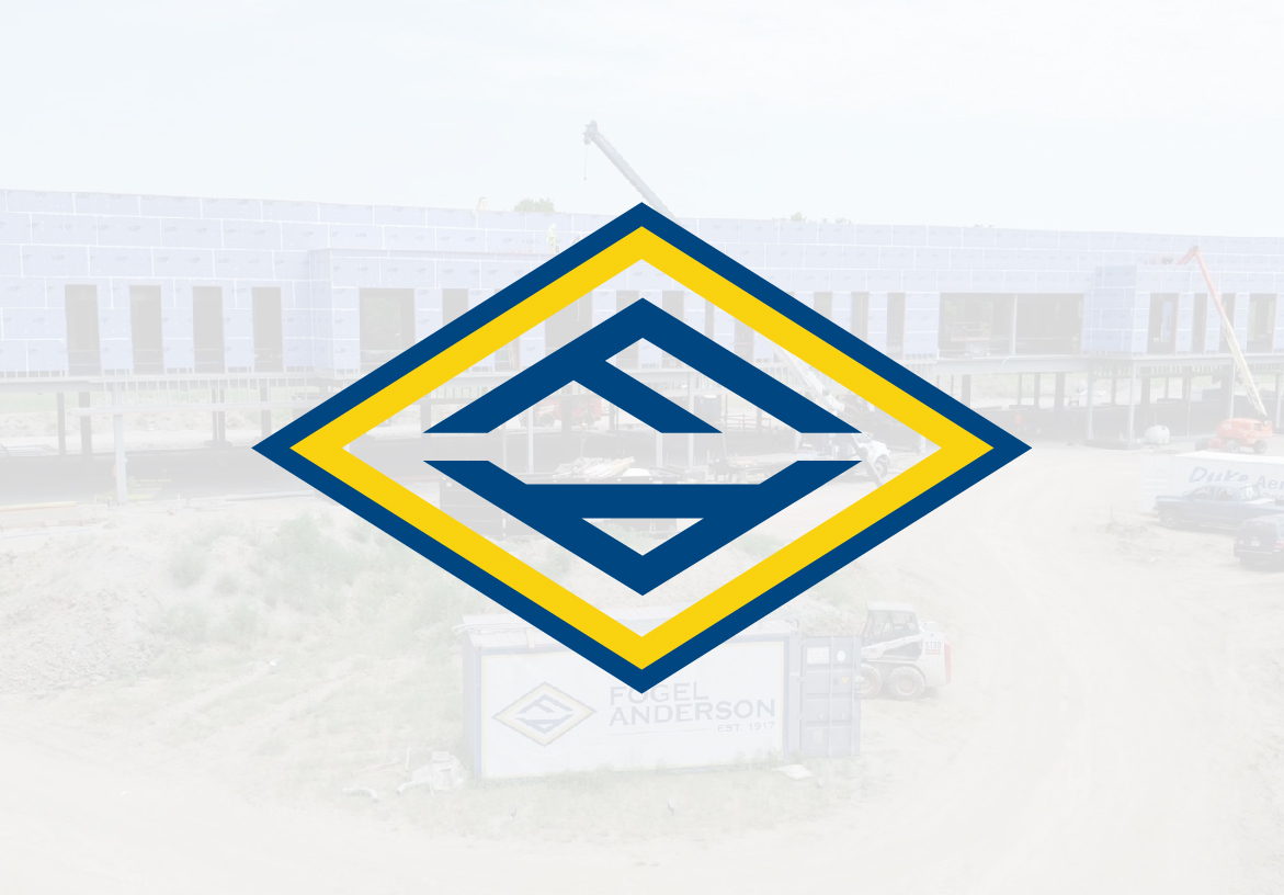 Fogel Anderson diamond logo icon featuring the 'FA' monogram in blue and yellow, overlaid on a large commercial construction site background.