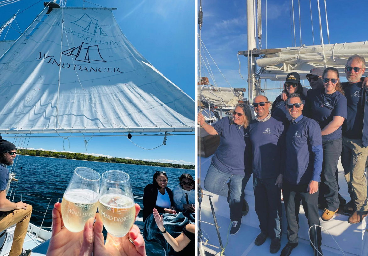 Guests enjoying a luxury sailing experience on the Wind Dancer, featuring a toast with champagne glasses against a backdrop of blue water.