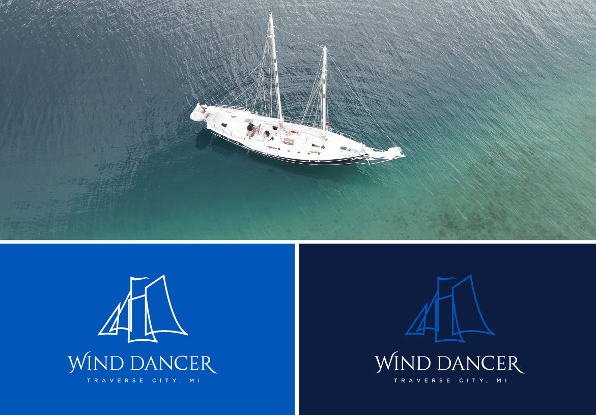 Aerial drone view of the Wind Dancer schooner sailing in clear green waters, paired with the official navy blue branding blocks.