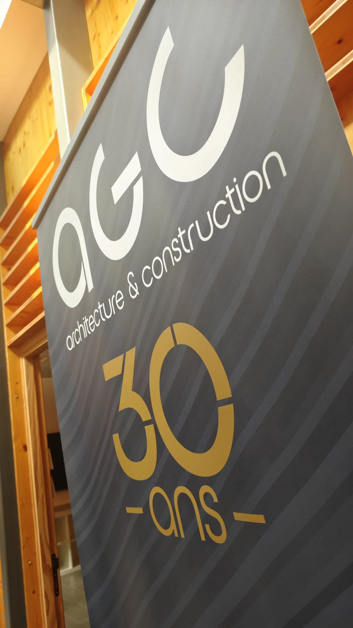 Close oblique view of the AGC wordmark and gold 30 years anniversary mark printed on a banner