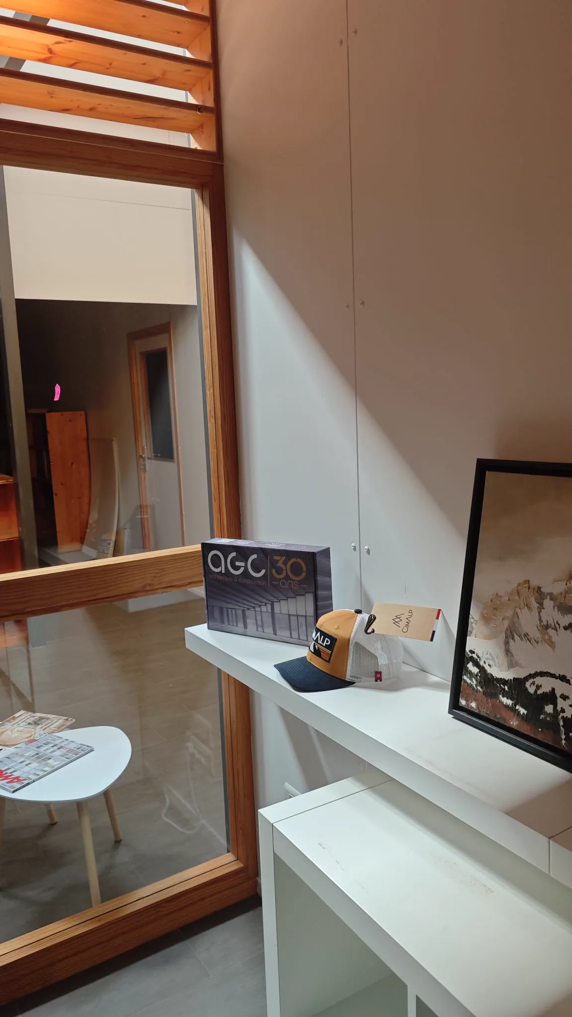 AGC office shelf displaying an anniversary presentation box, cap and architectural artwork