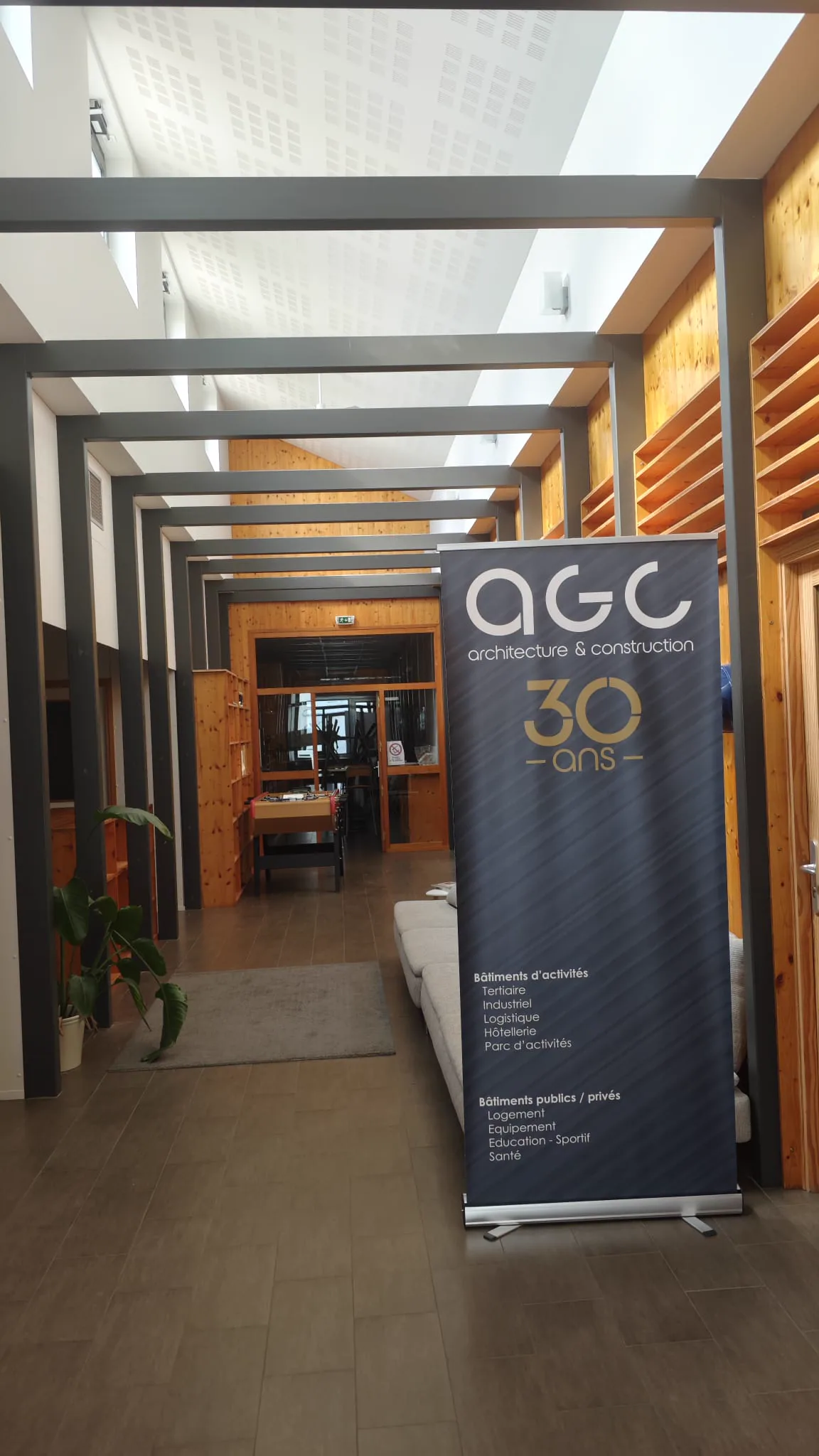 Full-height AGC 30 years anniversary banner standing in the Rovaltain office interior