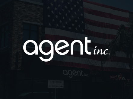 White AGENT INC. logo in sleek typography, set against a dark and subtly lit American flag background, representing their real estate services.