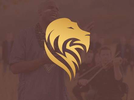 Gold lion head logo symbol for singer Alex Boyé, overlaid on a moody, soft-focus background of a musical performance.