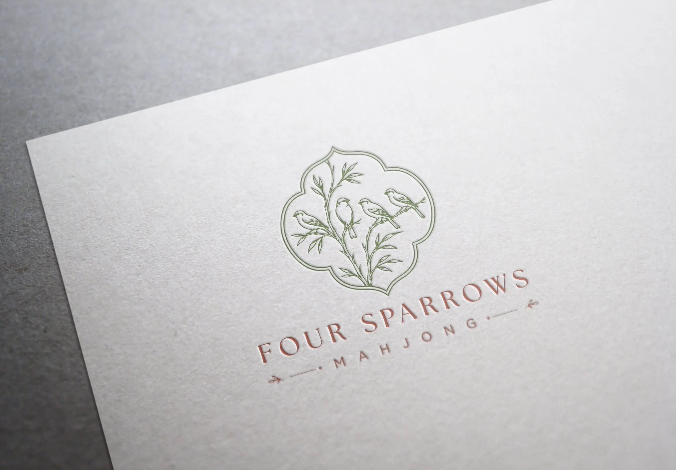 Letterpress detail of the Four Sparrows Mahjong logo printed on textured ivory paper