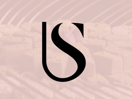 Elegant black 'Sb' monogram logo for Sprinkles Bakery Kuwait, displayed on a textured soft pink background representing premium confectionery.