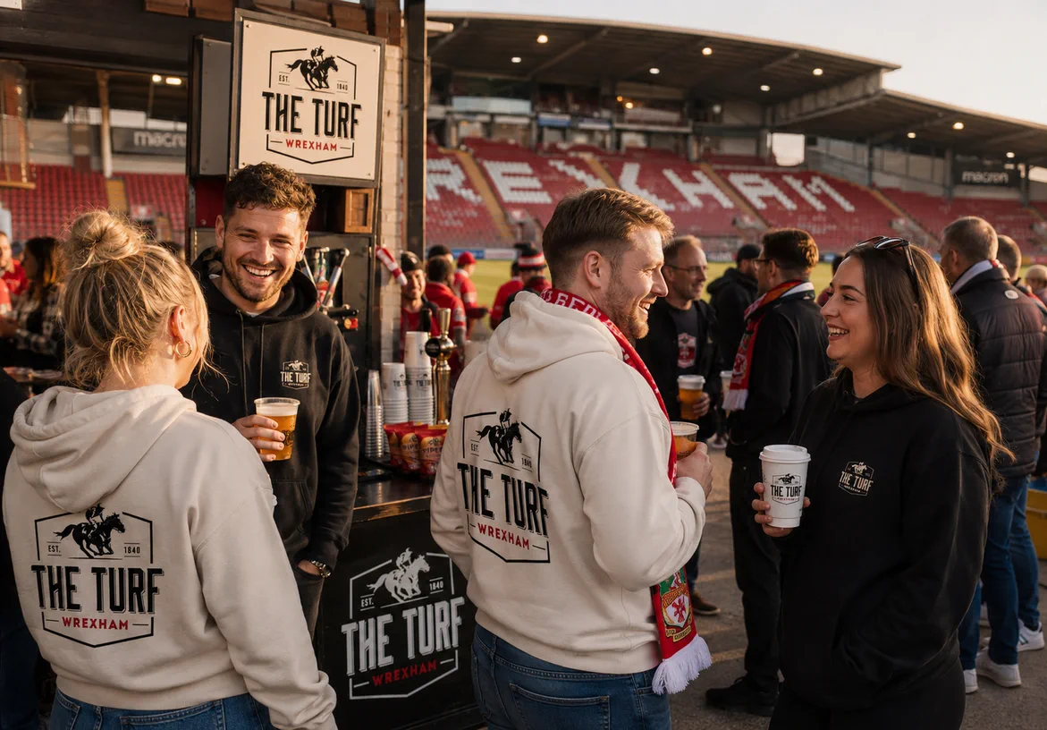 Matchday fans wearing The Turf branded hoodies inside the Wrexham stadium stands