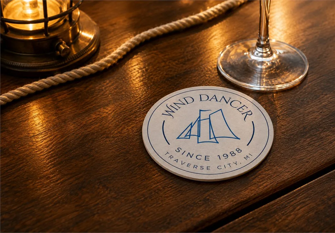 Wind Dancer branded coaster on a wooden table with rope and wine glass