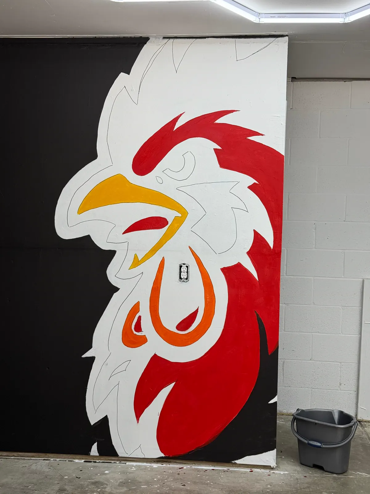 Close view of Wake Up Sports rooster mural paint blocking with red and yellow areas being filled