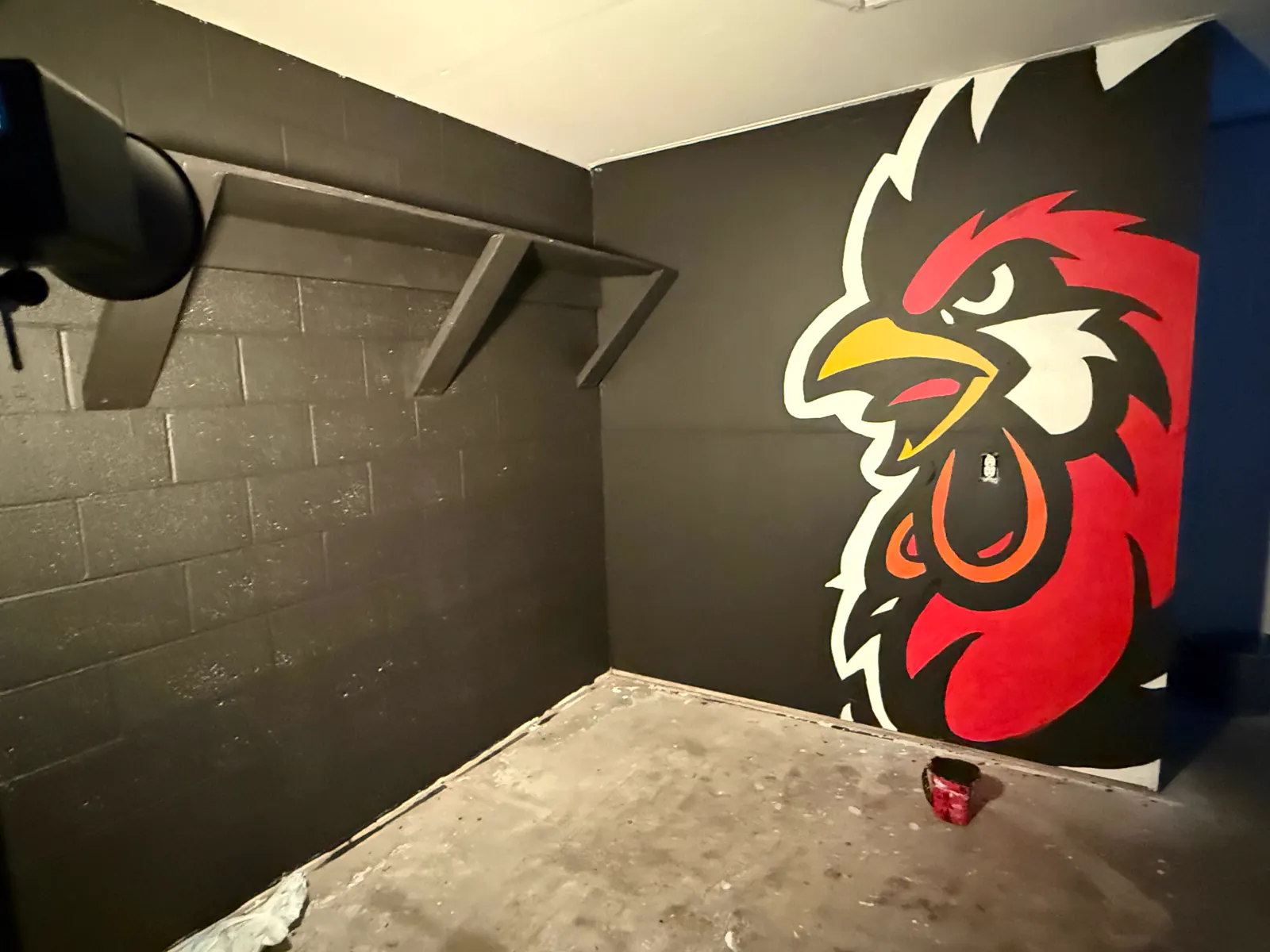 Wake Up Sports rooster mural viewed from the studio corner under warm lighting