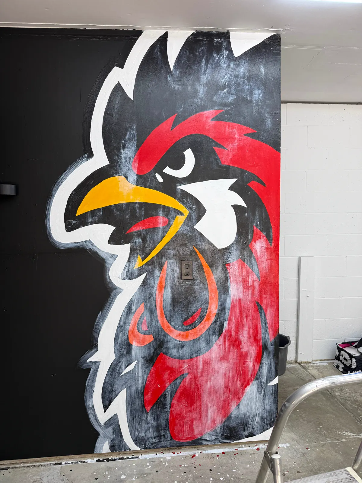 Wake Up Sports rooster mural detail showing red, yellow, white, and black paint fill progress