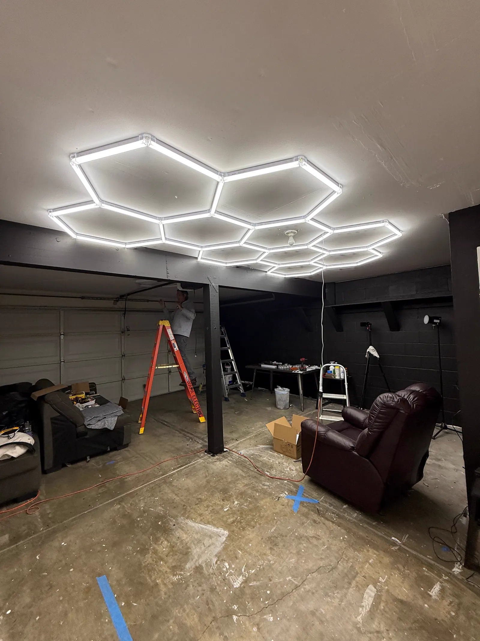 Wide view of the Wake Up Sports studio buildout with hex ceiling lights being installed