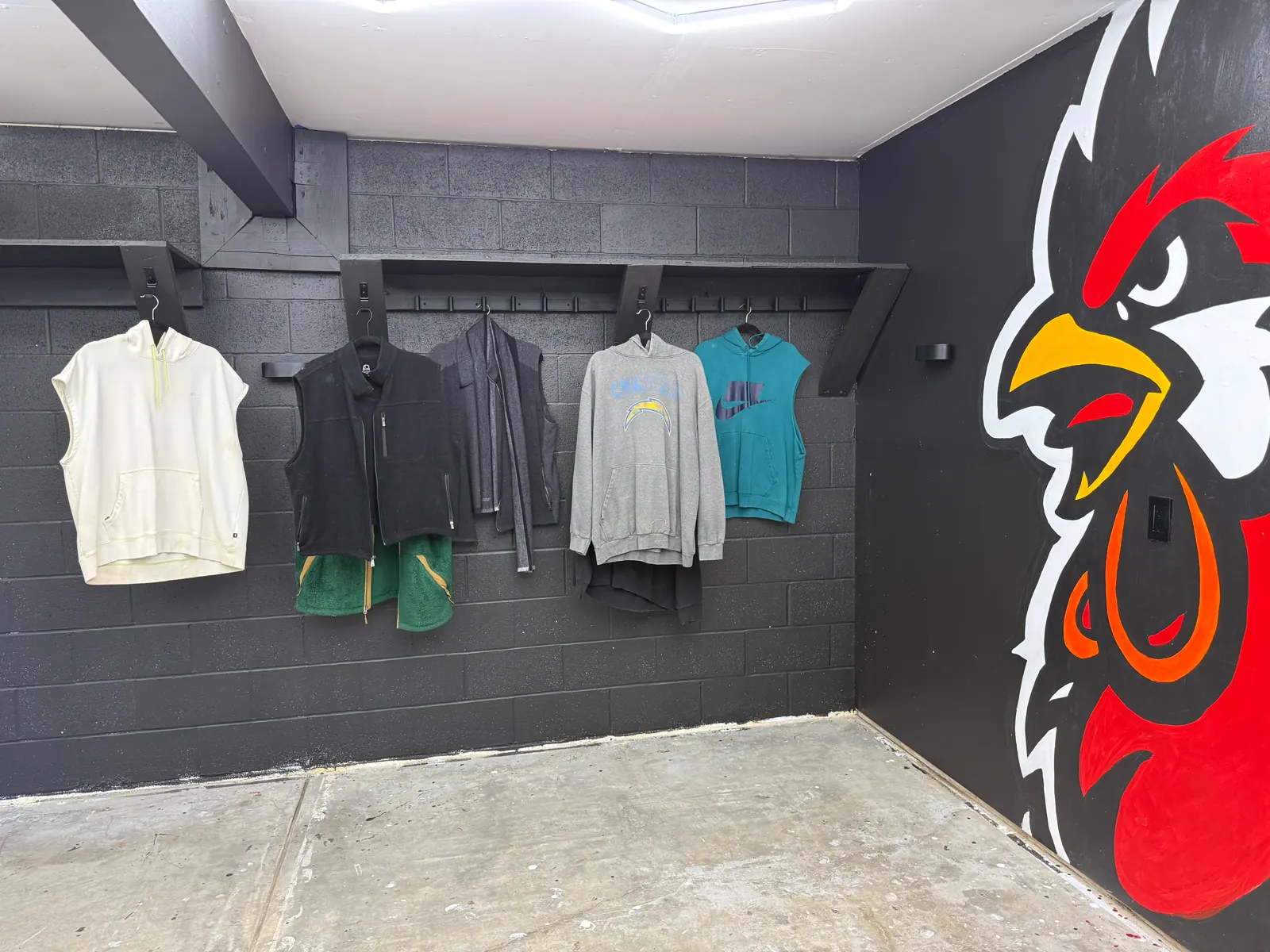 Wake Up Sports apparel displayed beside the rooster mural inside the studio